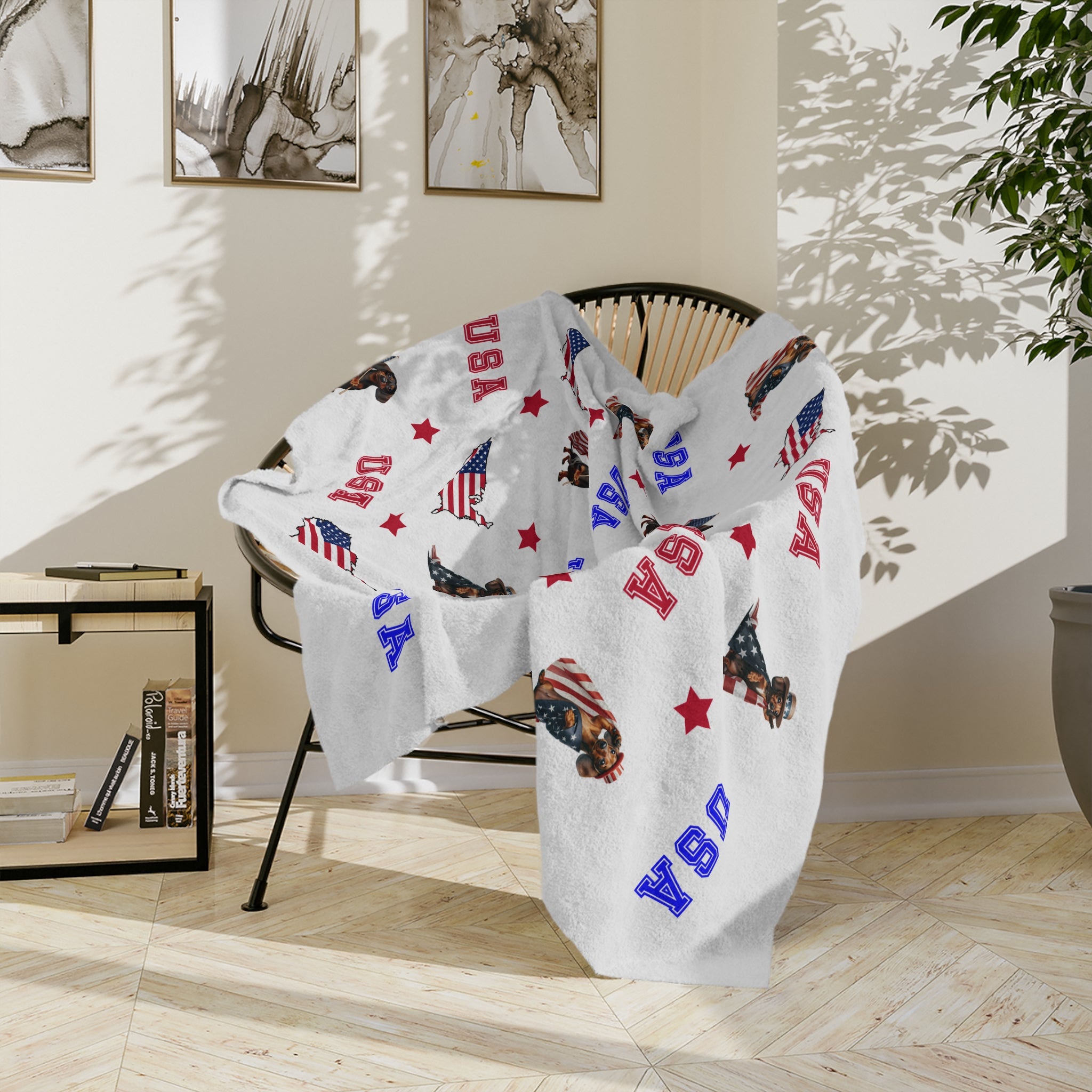 Blanket with 'USA' and flag patterns draped over a chair in a room with a plant and books.